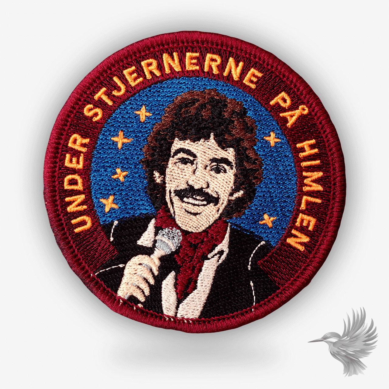 Rundt broderet patch med Tommy Seebach og teksten “Under stjernerne på himlen” – rød og blå hyldest til dansk popmusik