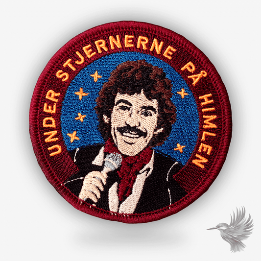 Rundt broderet patch med Tommy Seebach og teksten “Under stjernerne på himlen” – rød og blå hyldest til dansk popmusik