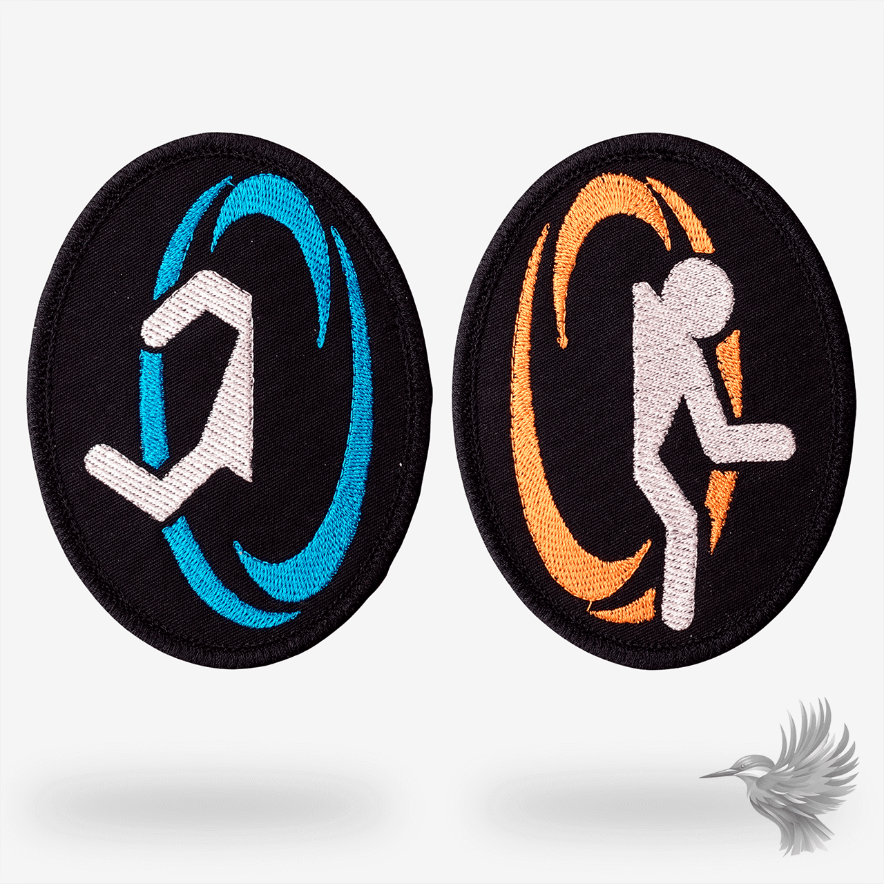 To broderede patches med figurer der går gennem blå og orange portal game – inspireret af computerspillet Portal