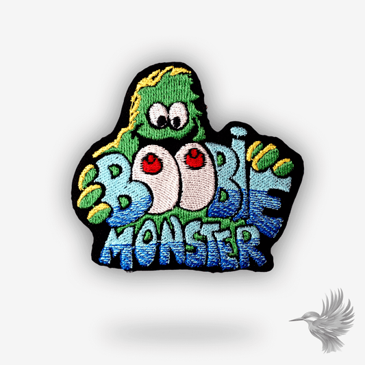 Broderet patch med farverigt monster og teksten “Boobie Monster” – humoristisk design med bryster i cartoon-stil
