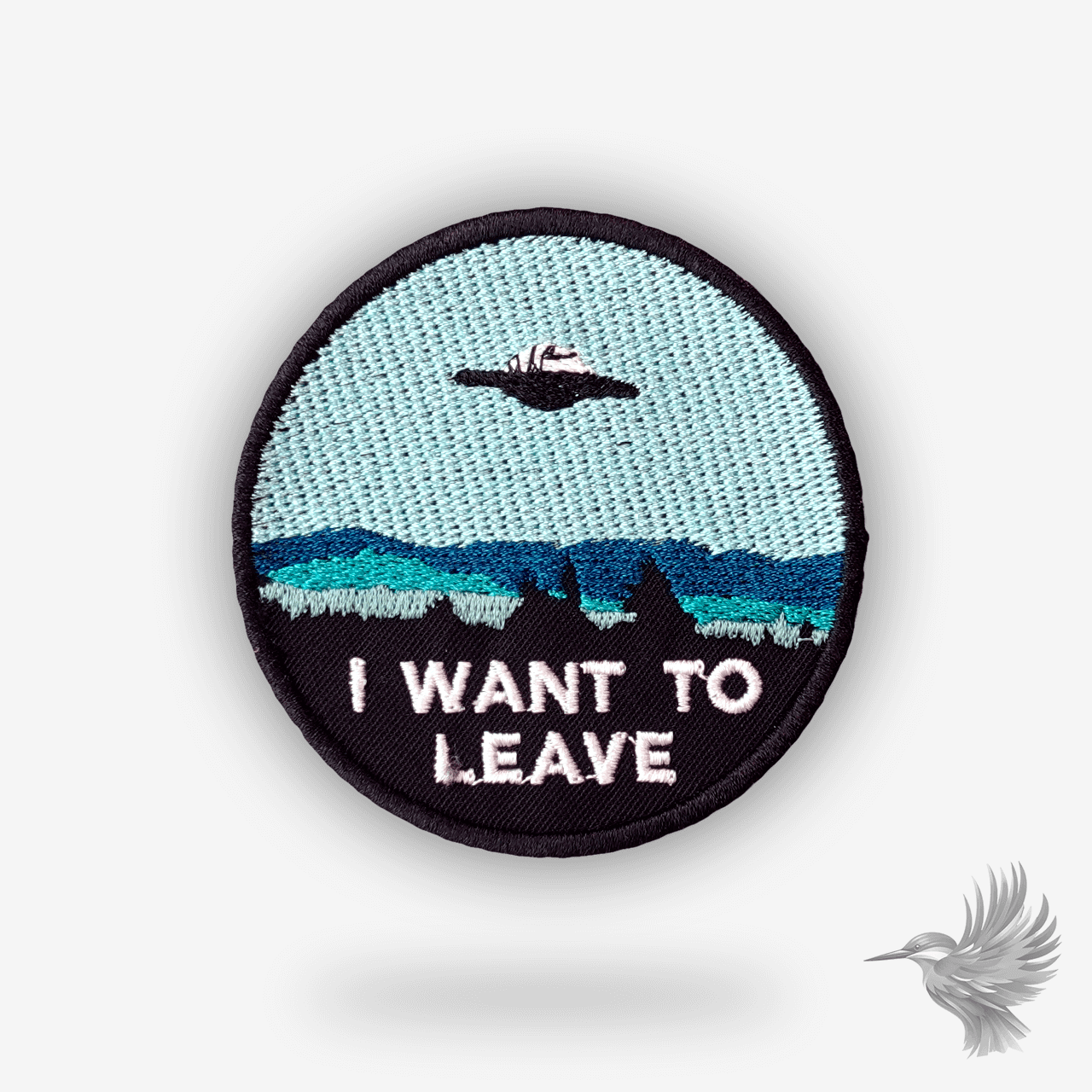 Broderet patch med UFO over træer og teksten “I want to leave” – ovalt mærke i blå og sort