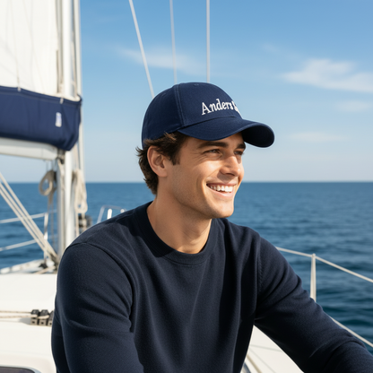 Navy Blue CAP Kasket med Egen Tekst og Broderi med broderet navn Anders Sand på en smilende mand.