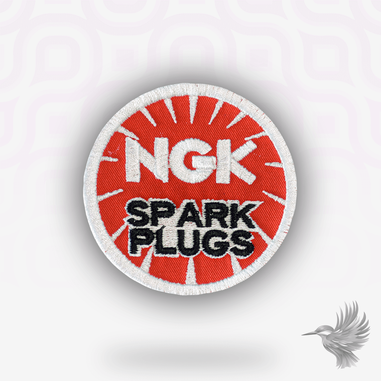 NGK Spark Plugs patch strygemærke med rød baggrund og hvitt logo, symbol på motorsport og mekanisk perfektion.