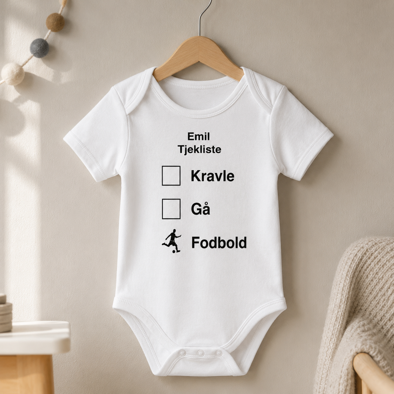 Personlig babybody med navnet Emil og tjekliste på træbøjle