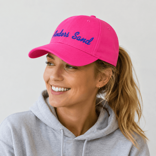 Pink CAP Kasket med Egen Tekst og Broderi på en glad kvinde med en grå hættetrøje.
