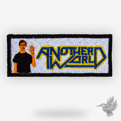 Another World patch strygemærke broderet retro gamingmotiv med karakter og logo i blå og gul.
