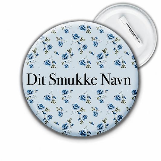 Personligt navnebadge med blå blomster og teksten Dit Smukke Navn