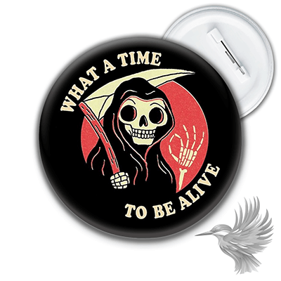 Sarkastisk badge med dødningehoved med teksten 'What a Time to Be Alive' og grinende dødningefigur.